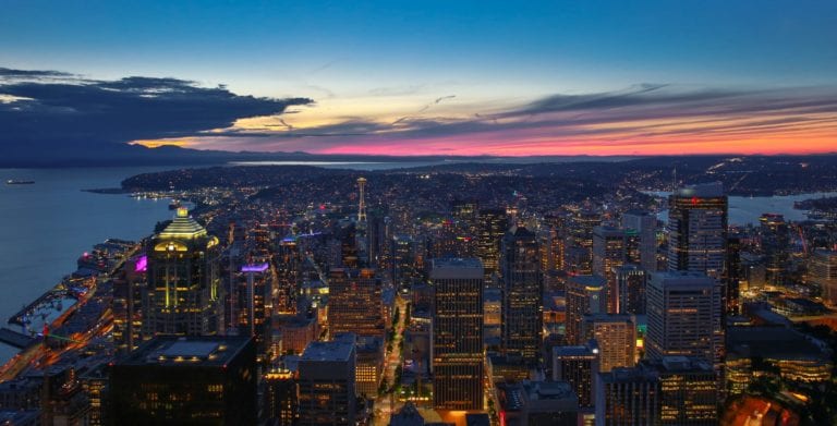 Norte de Seattle vista do alto com Space Needle aparecendo e o céu em tons de laranja do entardecer