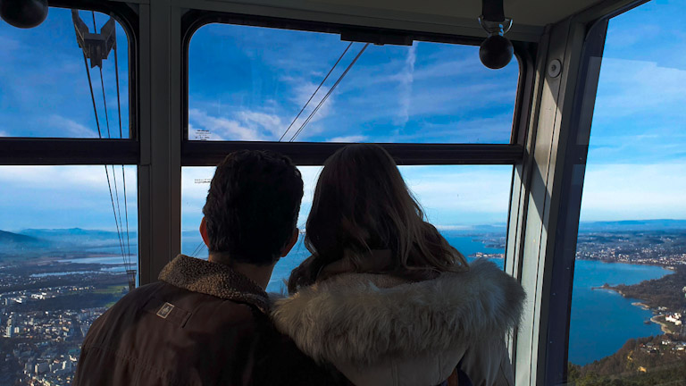 O que fazer em Bregenz, na Áustria: o encontro da montanha com o Lago Constança (Bodensee) 3 Guto e Chai de costas admirando De dentro do bondinho do Pfanderbahn, o teleférico da Montanha Pfander em Bregenz