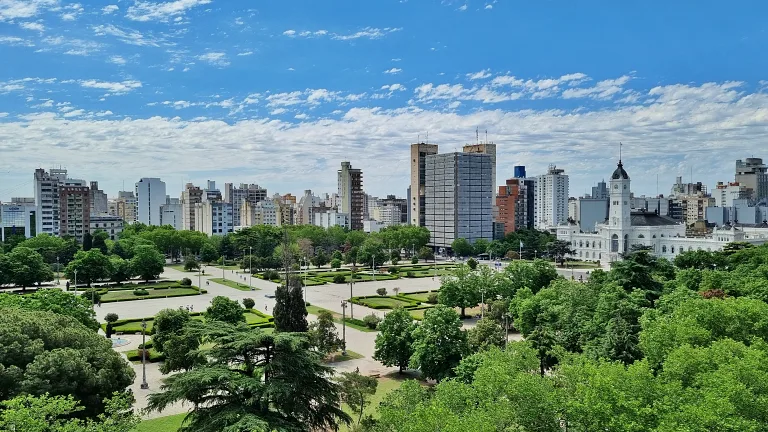 Onde ficar em La Plata: Conheça Dazzler by Wyndham La Plata 6 Plaza Moreno em La Plata com área verde e caminhos pavimentados e ao fundo à direita, destaca-se o Palácio Municipal de La Plata. Mais ao fundo, o skyline urbano.